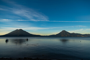 Puesta de sol a la orilla de Lago Atitlán  rodeado de zona montañosa del suroeste de Guatemala - obrazy, fototapety, plakaty