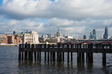 Beautiful view of London skyline from Riverbank. Old wooden pier, Saint Paul Cathedral and skyscrapers. Cloudy day, sunset.