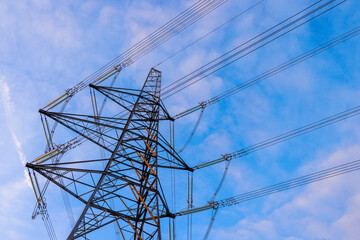 The setting sun reflects on an electricity pylon against a blue sky