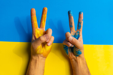 Stop war, conflict between Ukraine and Russia. A man wearing the colors of the Ukrainian flag and making the victory sign