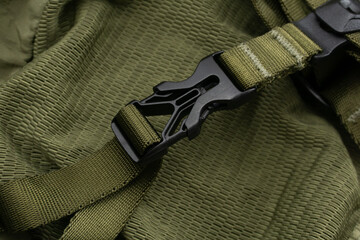 Detail of a khaki backpack with fastex, netting and a sling close up