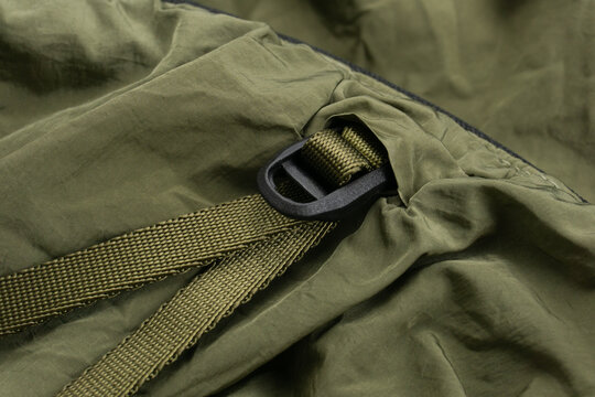 Detail of a khaki backpack with fastex and a sling close up