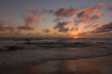 Fototapeta na wymiar playa con olas tranquilas en medio del ocaso o puesta de sol