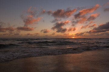 Naklejka na ściany i meble playa con olas tranquilas en medio del ocaso o puesta de sol