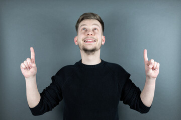 Junger Mann zeigt mit zwei Fingern nach oben Portrait