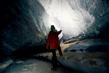 A woman explores an ice cave on a glacier near Almaty, Kazakhstan