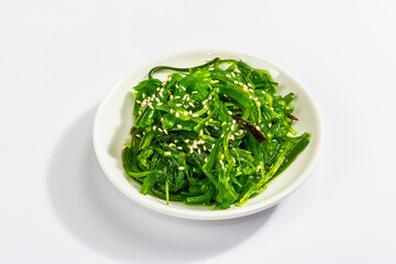 Chuka Seaweed Salad with sesame seeds isolated on white background. Trendy hard light, dark shadow