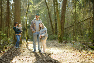 Fototapeta premium Young father and his three kids hiking in the woods. Family of four having fun on a walking trail on sunny spring day.