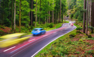 Obraz premium A road among the forest. Fast traffic. A blur of car lights. Landscape in evening time.