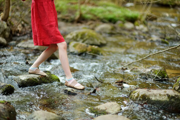 Adorable young girl having fun during a hike in the woods on beautiful sunny spring day. Active family leisure with kids.