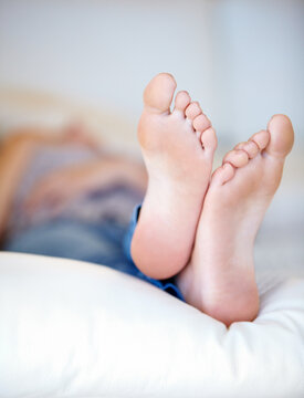 Feet up. Closeup of a young womans feet as shes lying on her bed.