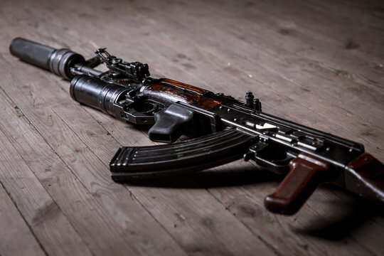 Kalashnikov assault rifle with suppressor isolated on wooden background