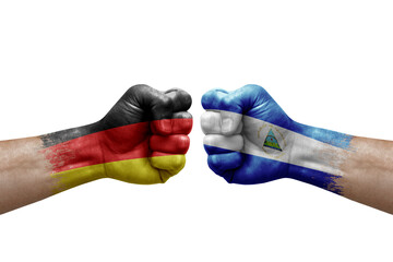 Two hands punch to each others on white background. Country flags painted fists, conflict crisis concept between germany and nicaragua