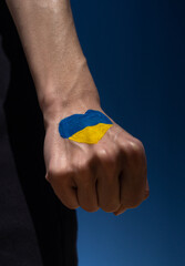 female hand fist painted in Ukraine flag colors yellow-blue in heart shape. Stop war between Russia and Ukraine. Solidarity with Ukraine, power of Ukraine, patriotism and Kiev, strength and power
