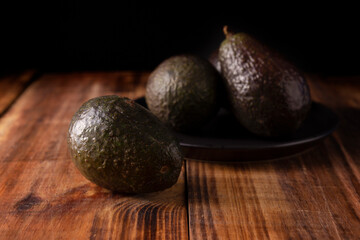 Whole Mexican avocado (persea americana) on rustic wooden table. Main ingredient to prepare guacamole.