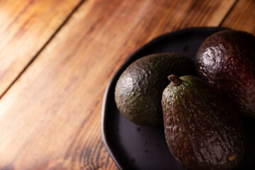 Mexican avocado (persea americana) on rustic wooden table. Main ingredient to prepare guacamole. Close up image with copy space.