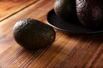 Mexican avocado (persea americana) on rustic wooden table. Main ingredient to prepare guacamole. Close up image with copy space.