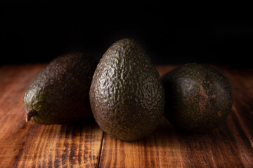 Whole Mexican avocado (persea americana) on rustic wooden table. Main ingredient to prepare guacamole. Close up image