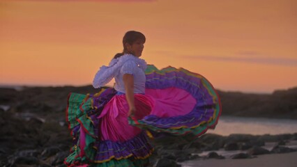 Slow Motion footage of a Costa Rican woman in traditional Guanacaste dress dancing in sunset light at the beach