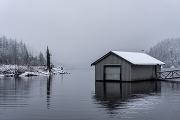 Boat house on foggy white lake in winter after fresh snow