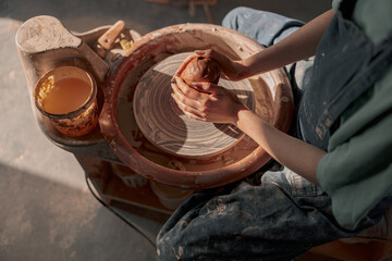 Clay artist modeling product on potter wheel in workshop