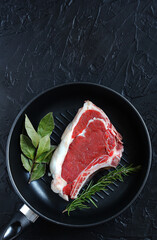 raw steak entrecote in a pan, grill, top view, copy space, dark background