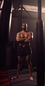 A Vertical Video Portrait Of A Hispanic Bodybuilder In An MMA Gym. Shot In A Crossfit Boxing Gym With Low Key Lighting And A Scattering Of Haze. Captured On Red Digital Cinema Camera 