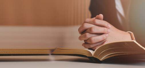 A Woman Hands folded in prayer on a Holy Bible in church concept for faith, spirituality and...