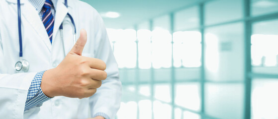 Male doctor showing thumbs up on blur background, hospital and area for advertisement