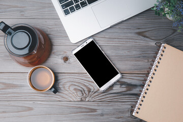 Office table with blank notebook and laptop