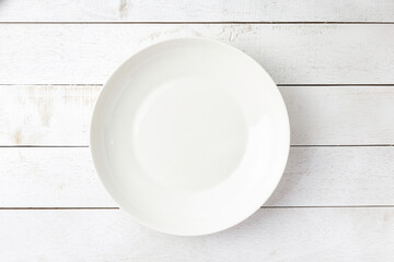 Blank white dish on a wood background / Top view above the wooden table with copy space for your recipe.