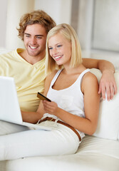 Searching for something for their new house. A happy young couple doing their online banking from the comfort of their couch.