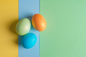 three Easter eggs lie on three colored backgrounds