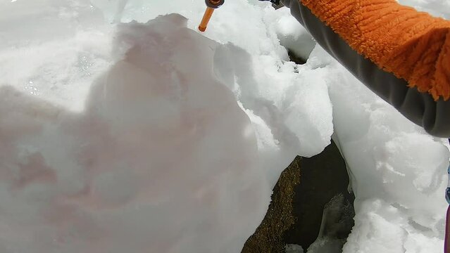 Man climbing ice waterfall with rope and ice axe