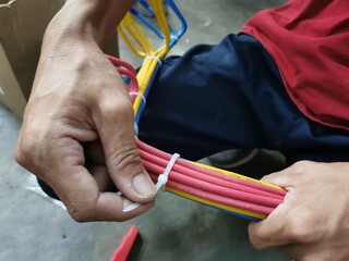 An electrical technician apply zip ties to a bundle of wires.