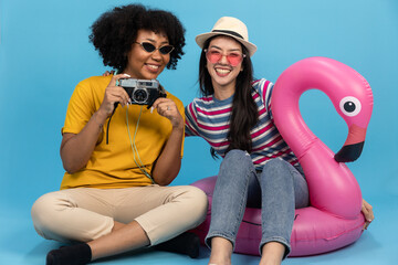 Happy smiling african and asian woman holding flamingo rubber ring and enjoying their summer...