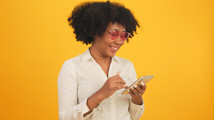 Happy smiling African American woman with afro hairstyle happy positive smile chat email mobile isolated yellow  color background.