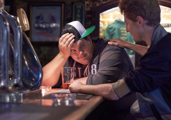 Cheer up Pal. A young man being consoled by a friend at the bar.