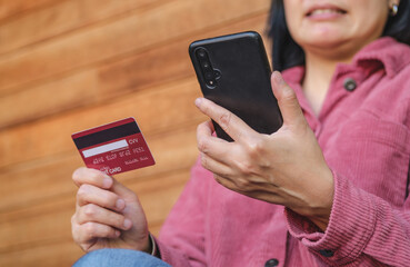 woman shopping online with credit card at coffee shop in outdoor.close up hand holding smartphone