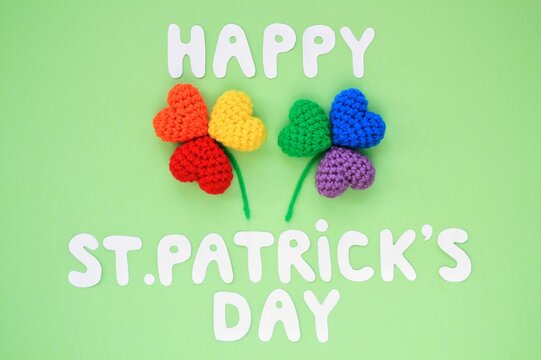Happy St. Patrick's Day lettering with rainbow lgbt shamrock leaves on green background. Flatly top view concept. 