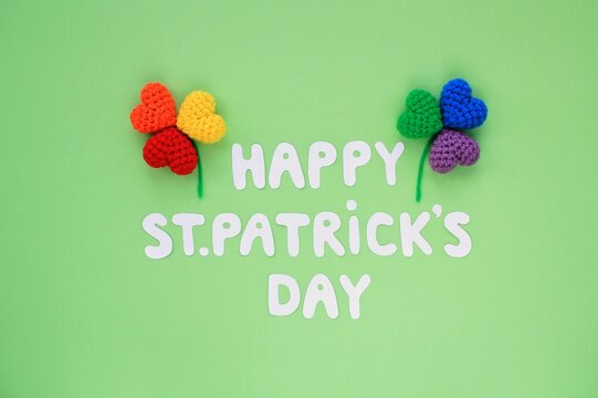 Happy St. Patrick's Day lettering with two rainbow lgbt shamrock leaves on green background. Creative minimalistic lay out concept. 