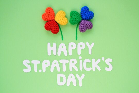 Happy St. Patrick's Day lettering with two rainbow lgbt shamrock leaves on green background. Creative minimalistic lay out concept. 