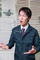 スーツに作業着を着た男が泣く