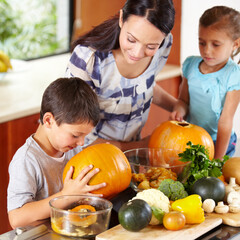 I think its ready. Shot of a mother helping her children carve pumpkins for halloween.