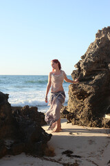  portrait of pretty female ship wrecked  model wearing  torn dress.  posing on the rocky  Ocean shoreline at sunset,