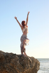  portrait of pretty female ship wrecked  model wearing  torn dress.  posing on the rocky  Ocean shoreline at sunset,