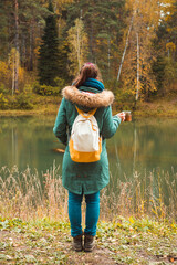 Young woman in autumn park hold mug with hot chocolate. Selective focus.
