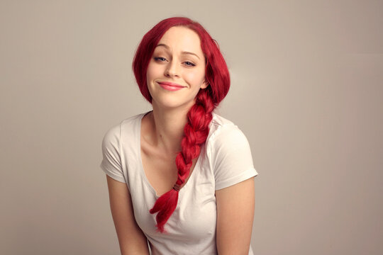 close up portrait of pretty female model with red hair in a braid, expressing emotion over the top facial expression on a studio background.