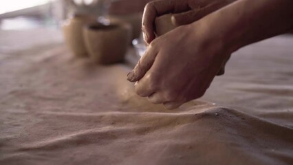 female hands of a potter knead and form a soft, wet piece of white clay. Preparation of clay material for making handmade pots. Ceramics in the process of being made close-up. Clay hand sculpting - Powered by Adobe