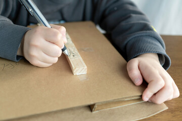 段ボールと木材で作品を作る子供の手。クラフト、自由工作